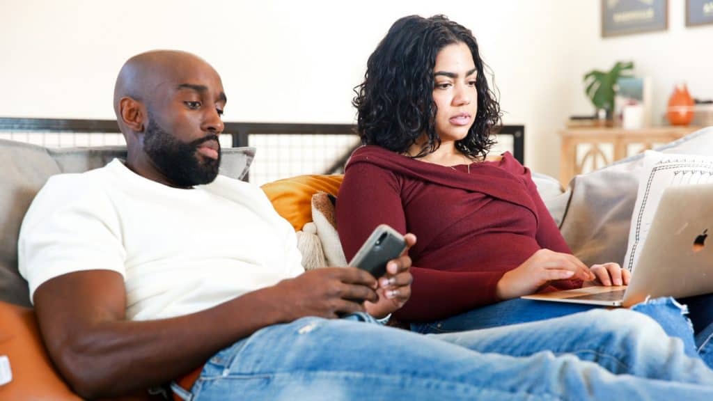 husband and wife distracted on electronic devices