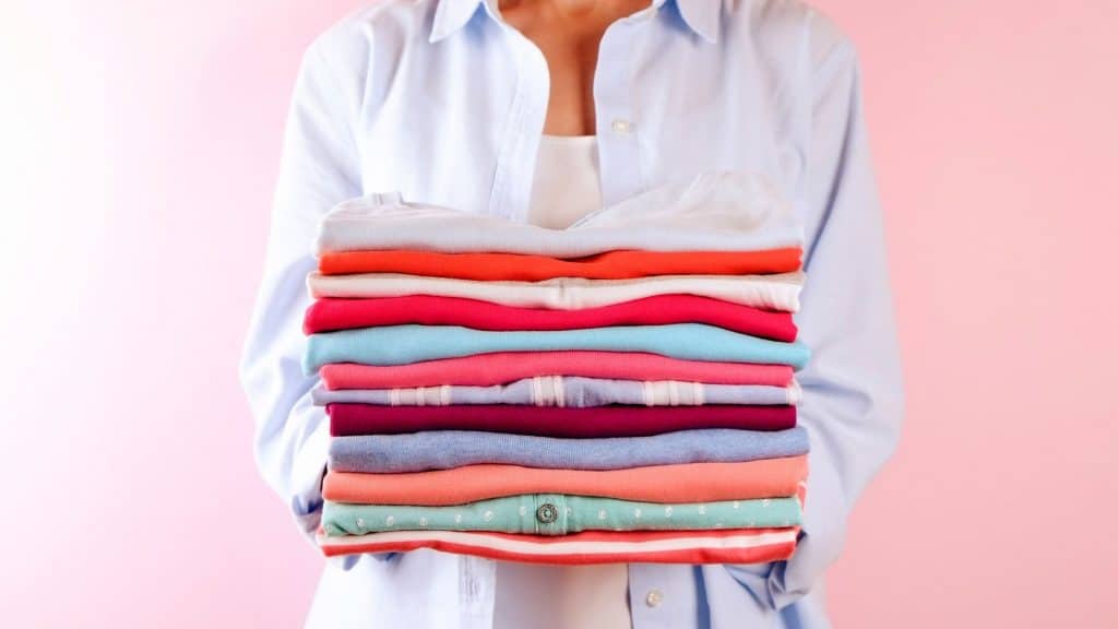 mom holding up folded clothes she finished from her side hustles ideas for moms 