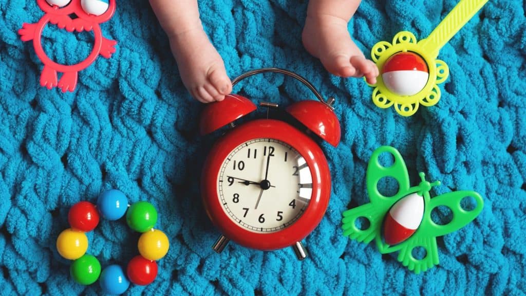 baby feet with clock and toys around